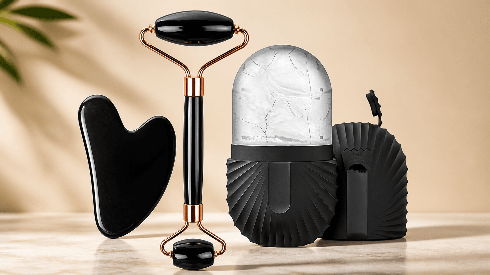 The black ice roller, gua sha and ice cup set lined up on a warm neutral background.